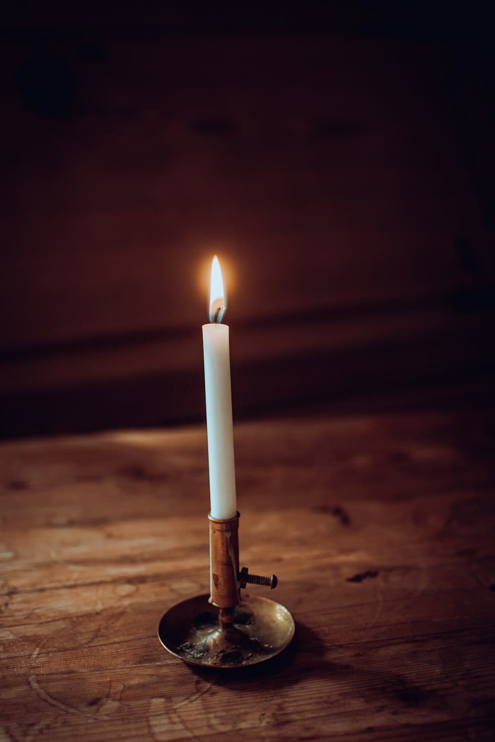 A single candle burning on a wooden table